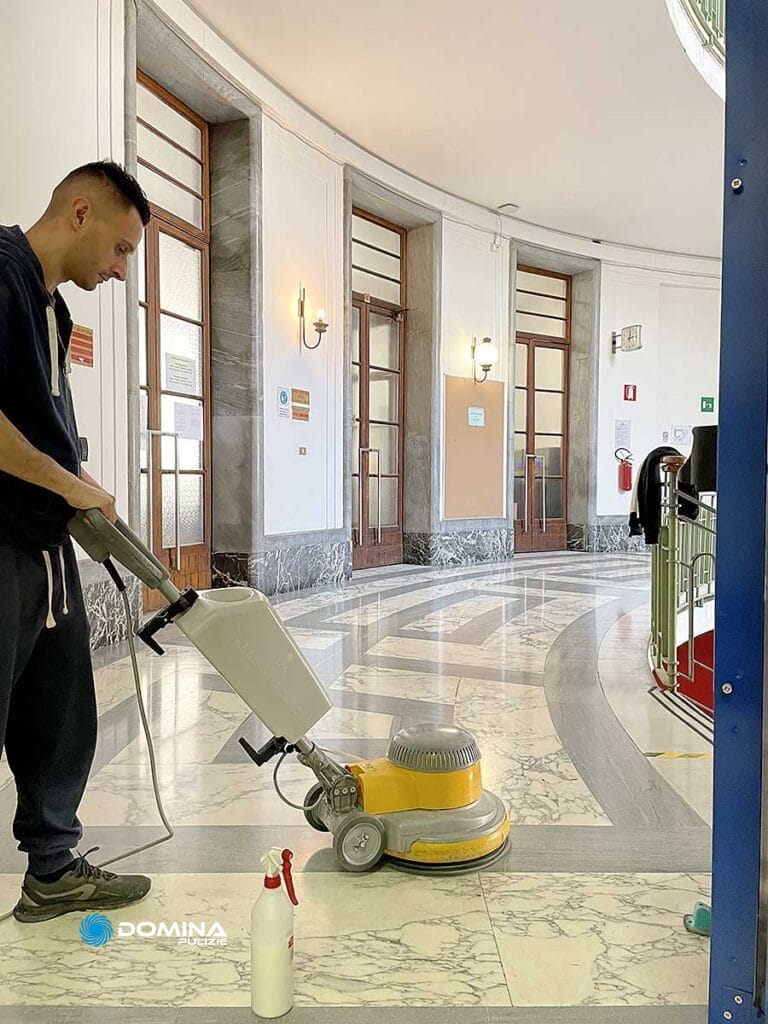 Un uomo che pulisce un pavimento di marmo con una macchina Pavimenti.