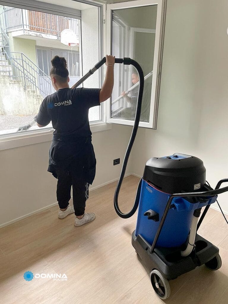 Una donna che pulisce una stanza con un aspirapolvere in un appartamento post ristrutturazione a Legnano.