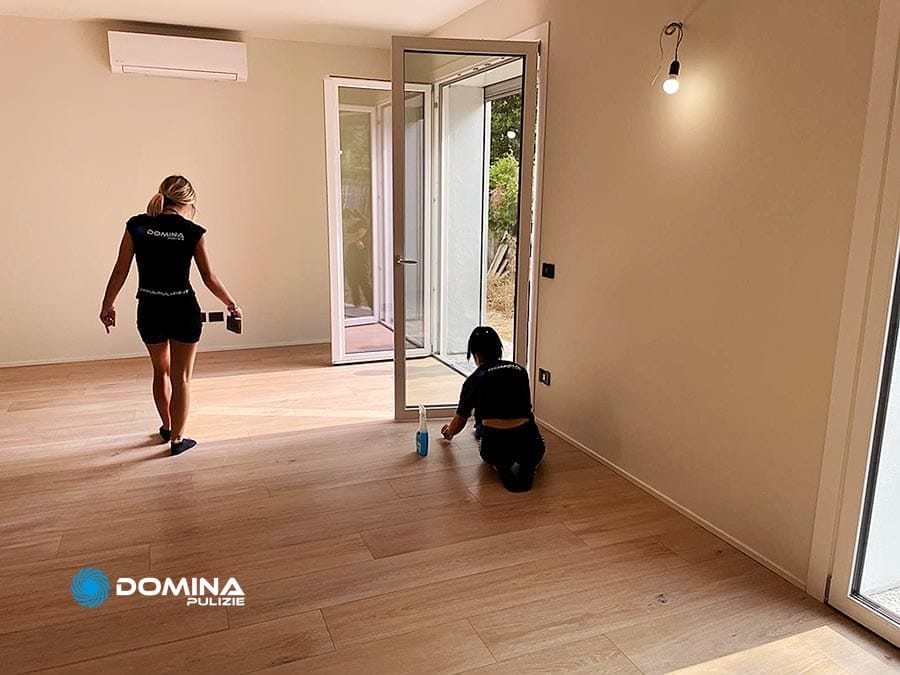Due donne puliscono una stanza con pavimenti in legno in un appartamento post ristrutturazione a Legnano.