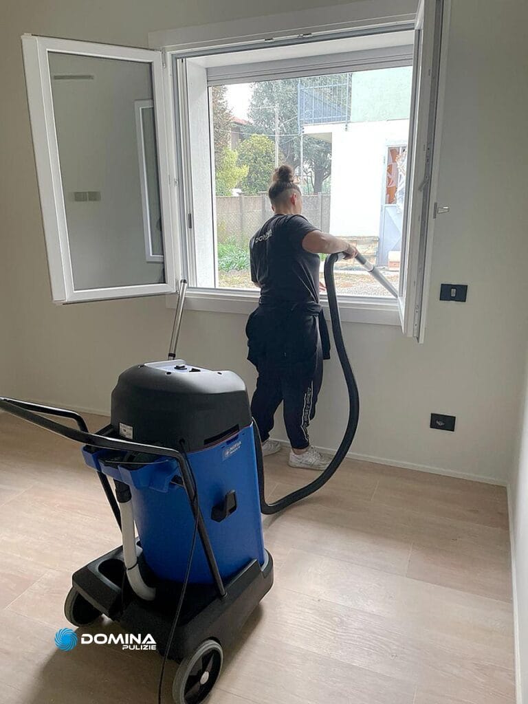 Una donna che pulisce una stanza con un aspirapolvere per un appartamento ristrutturato a Legnano.
