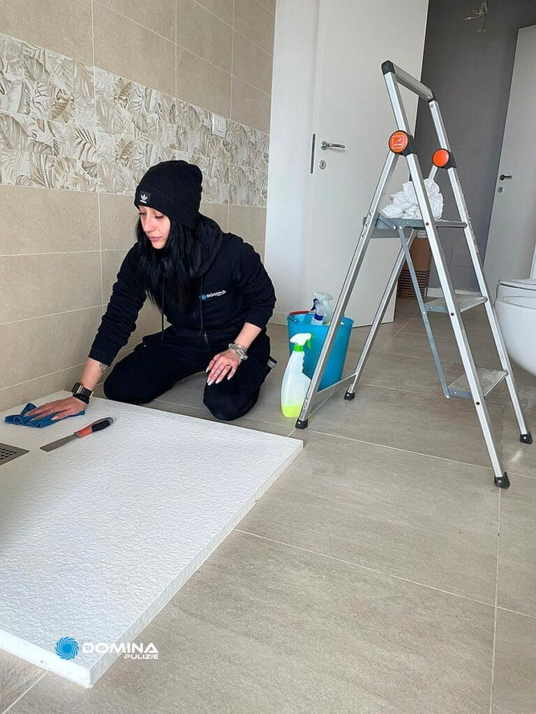Una donna sta pulendo il pavimento di un bagno dopo i lavori di ristrutturazione a Meda.