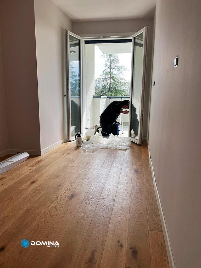 Un uomo sta lavorando al pavimento in legno di una stanza dopo un bel lavoro di pulizia e ristrutturazione in provincia di Monza Brianza.