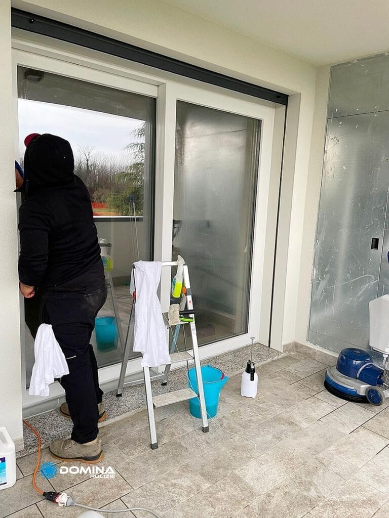 Una donna vicino ad una porta a vetri in provincia di Monza Brianza per la pulizia dei vetri delle finestre.
