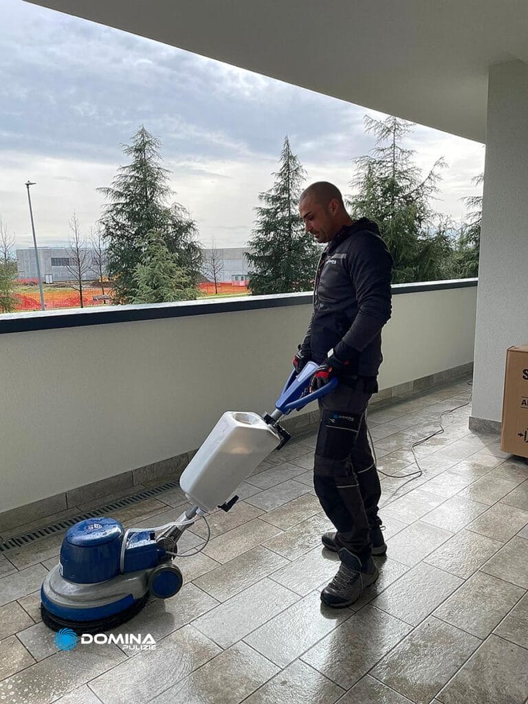Un uomo che usa una macchina per pulire il pavimento piastrellato di un appartamento dopo la ristrutturazione a Meda