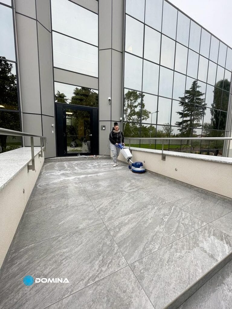 Un uomo sta pulendo i gradini di un edificio adibito a uffici.