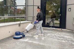 Una donna utilizza una macchina Rigenera Pavimenti per pulire un pavimento in grès a Varese.