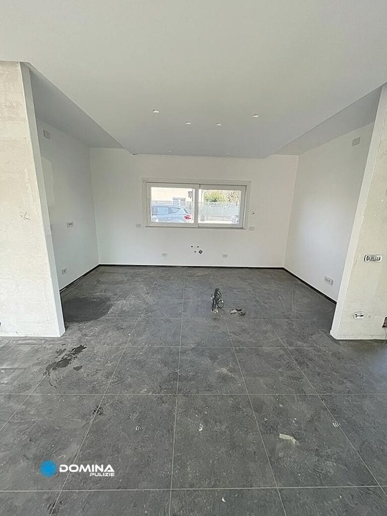 Camera non ammobiliata con pavimento piastrellato grigio e pareti bianche, prima delle pulizie post ristrutturazione a Rescaldina.