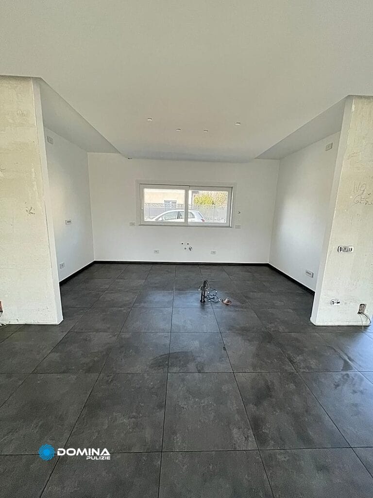 Camera non ammobiliata con pavimento piastrellato grigio e pareti bianche, dopo delle pulizie post ristrutturazione a Rescaldina.