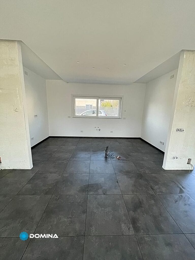 Camera non ammobiliata con pavimento piastrellato grigio e pareti bianche, dopo delle pulizie post ristrutturazione a Rescaldina.