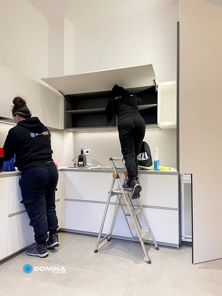 Due persone che lavorano alla pulizia profonda in una cucina moderna con mobili bianchi a Seregno.