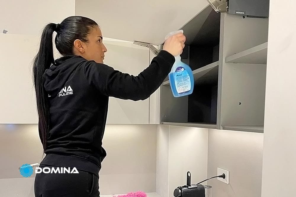 Una persona che pulisce un mobile da cucina a Seregno.