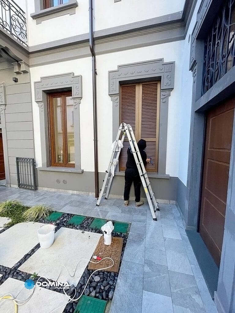 Una persona svolge attività di pulizie persiane all'esterno di un edificio a Seregno.