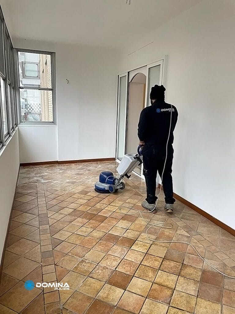 Un uomo con Esperienza Domina pulisce il pavimento piastrellato di una stanza con una monospazzola professionale.
