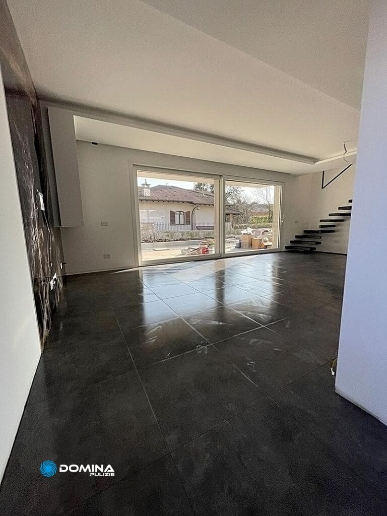 Un salone con pavimento piastrellato grigio e pareti bianche, dopo delle pulizie post ristrutturazione a Rescaldina.
