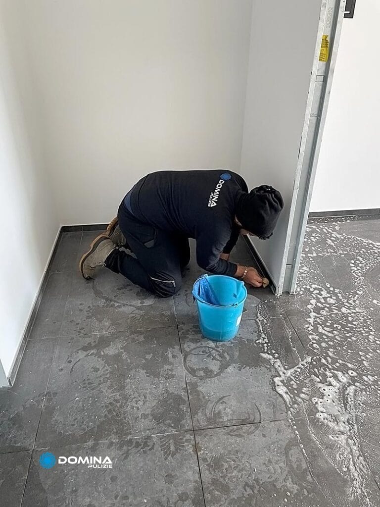 Persona che pulisce un pavimento insaponato con un secchio nelle vicinanze, parte del team dell'impresa di pulizie Rescaldina.