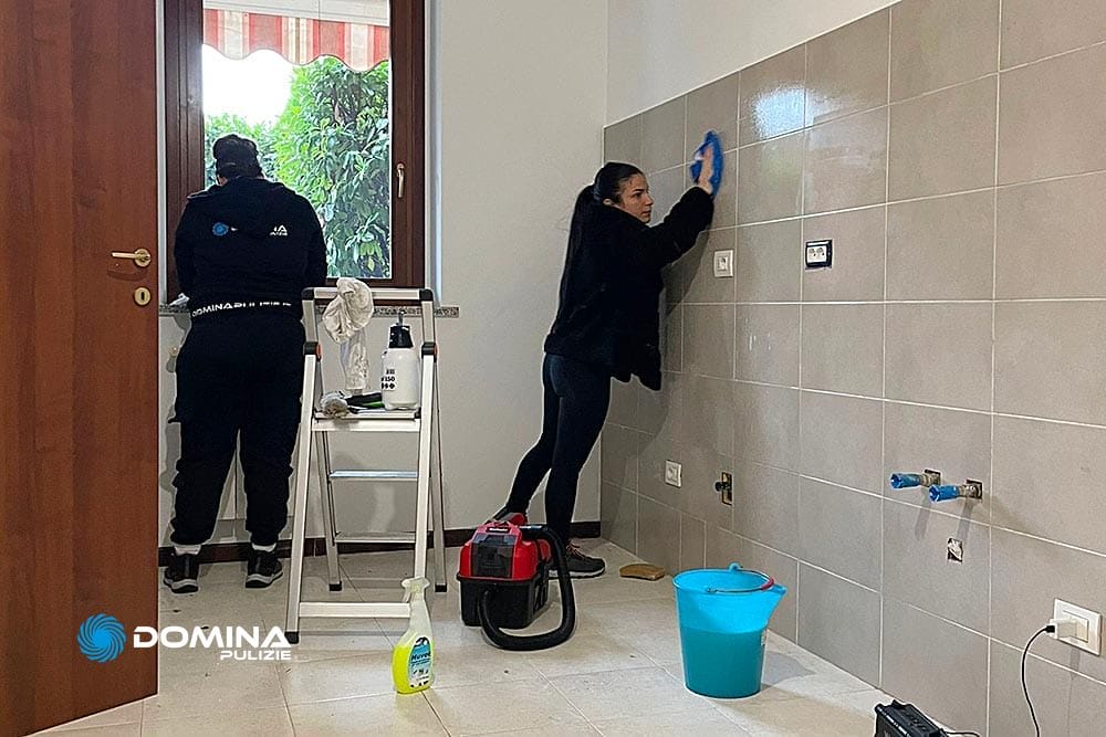 Due persone effettuano le pulizie post ristrutturazione Arluno, ripulendo le pareti all'interno di una stanza con attrezzi per la pulizia.