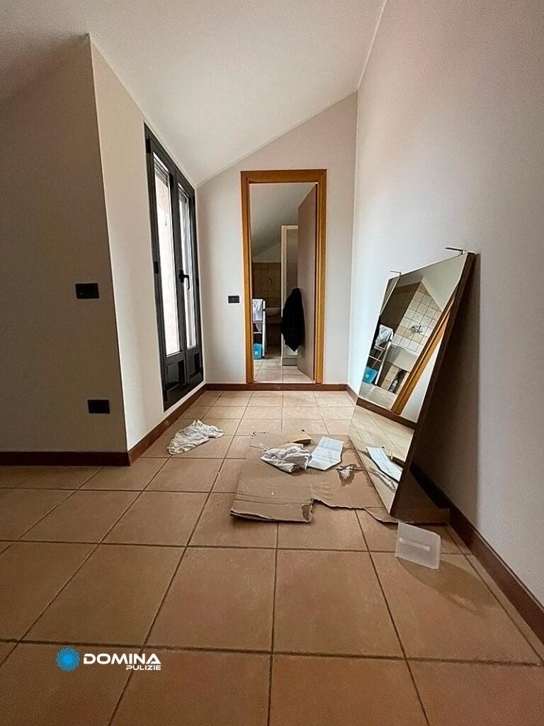 Una stanza, svuotata tranne uno specchio appoggiato e materiali da imballaggio sparsi sul pavimento, in attesa delle pulizie post ristrutturazione Senago.