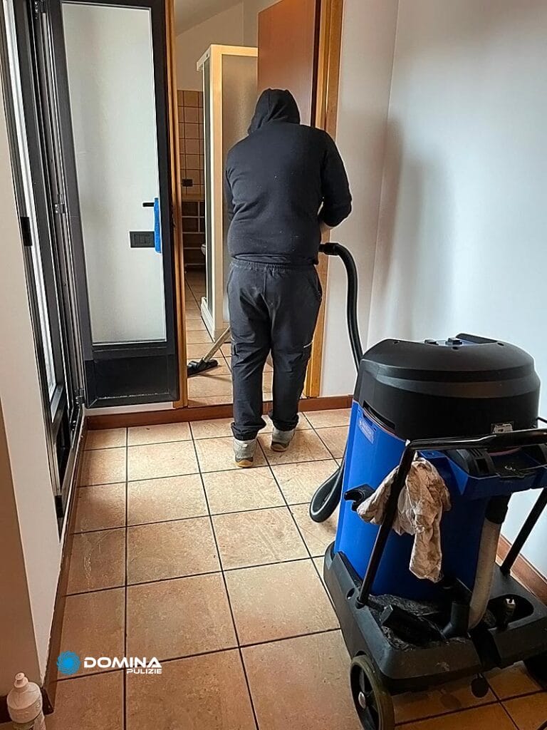 Una persona che pulisce un pavimento piastrellato con un aspirapolvere professionale dopo una ristrutturazione a Senago.