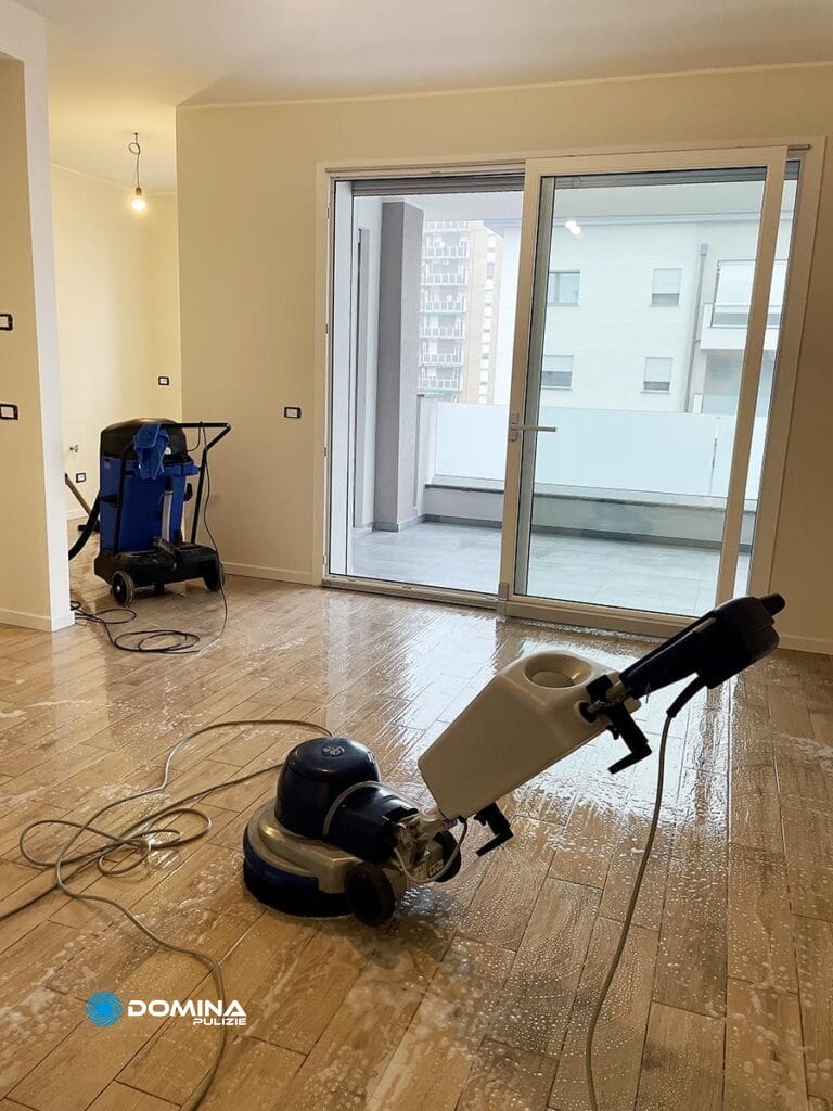 Una lucidatrice per pavimenti e un aspirapolvere in una stanza vuota con pavimenti bagnati, che indicano una Domina Pulizie la migliore impresa di pulizie a Monza.