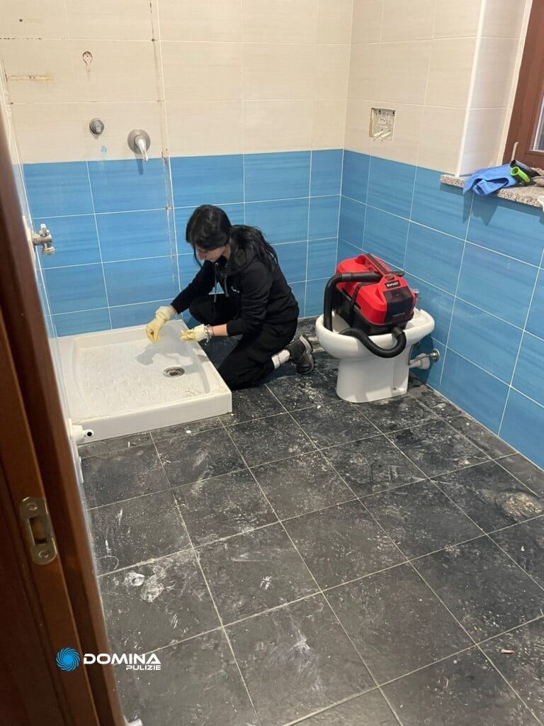 Una persona indossa guanti e attrezzatura protettiva effettua pulizie post ristrutturazione in una casa ad Arluno, pulendo il pavimento del