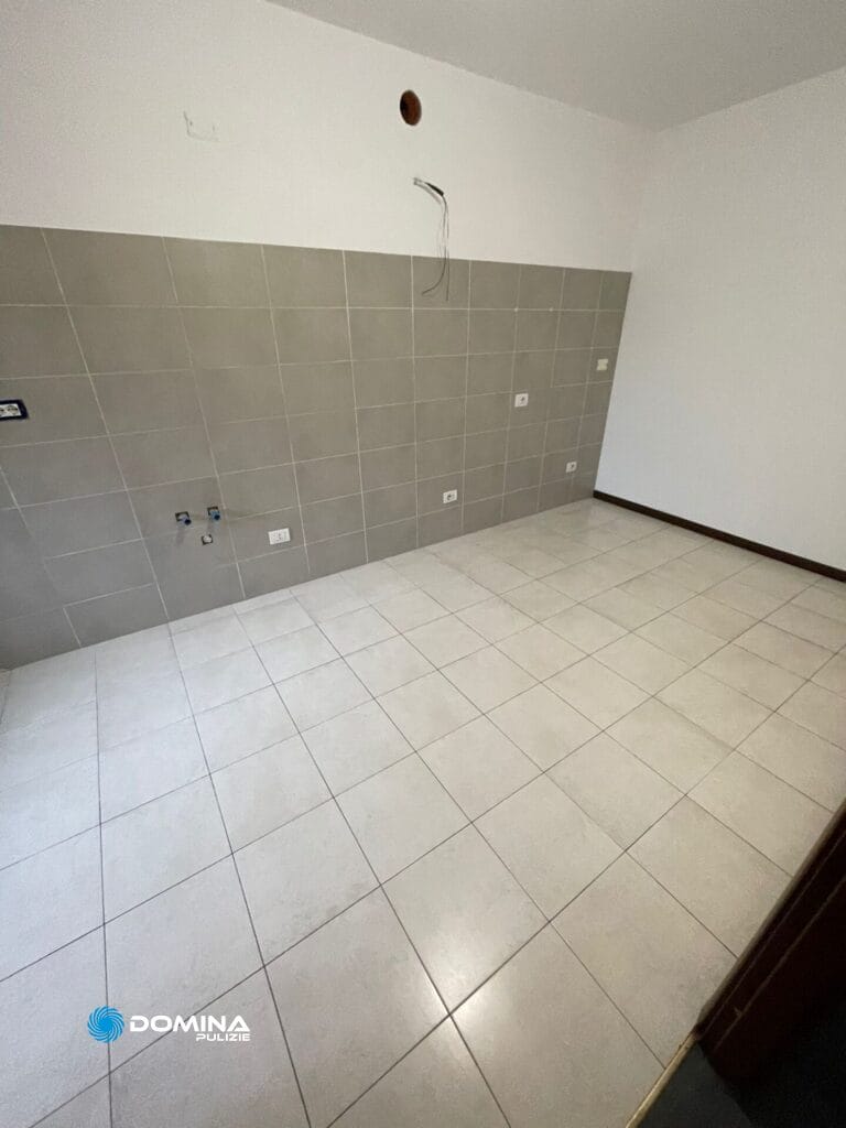 Una casa ad Arluno con un angolo vuoto, pareti piastrellate di grigio e pavimento piastrellato, in attesa di pulizie post r
