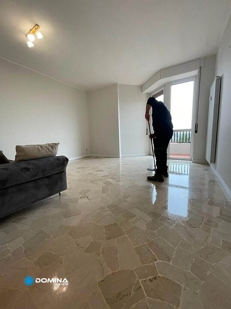 Persona che pulisce il pavimento in una stanza luminosa e vuota nell'ambito del servizio impresa di pulizie a Olgiate Olona.