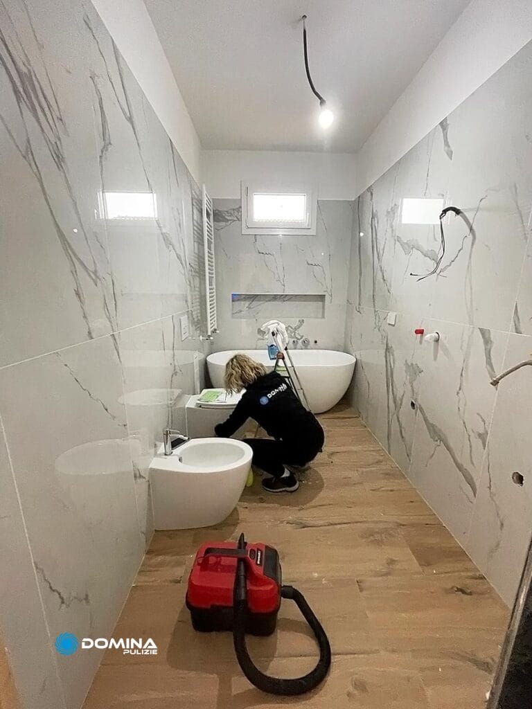 Una persona di Domina Pulizie pulisce un bagno in un appartamento a Senago dopo la ristrutturazione.