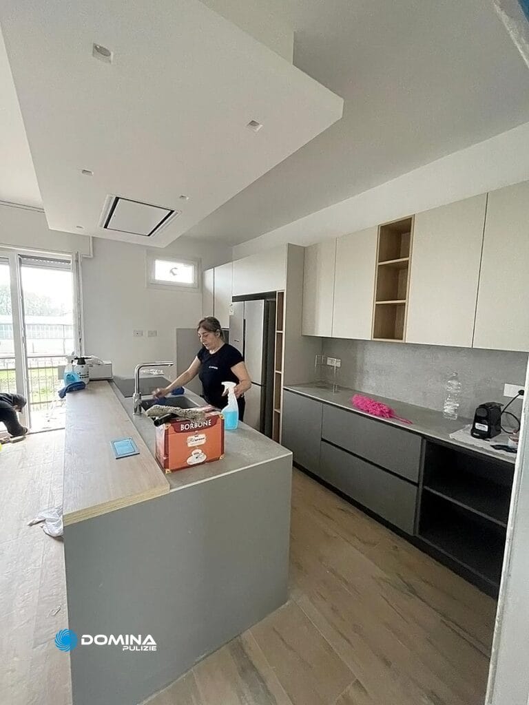 Persona che pulisce una cucina moderna in un appartamento a Senago dopo i lavori di ristrutturazione.