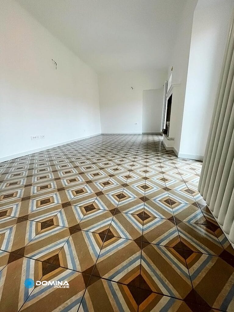 Una stanza vuota con pavimentazione a piastrelle a motivi geometrici e pareti bianche, recentemente resa brillante dall'impresa di pulizie a Bollate