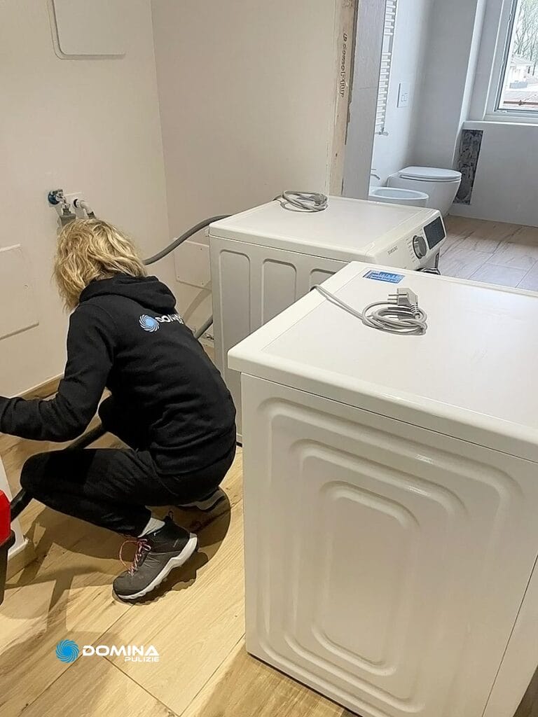 Persona che installa una lavatrice in una lavanderia, garantendo il mantenimento degli standard di pulizia post cantiere Milano.