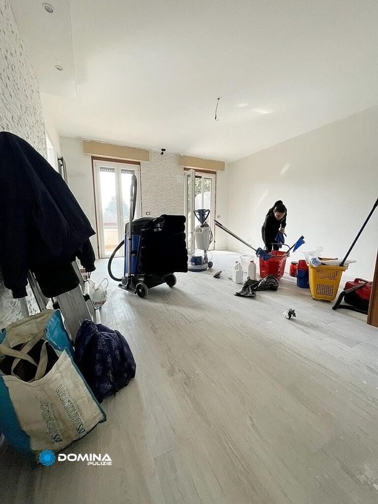 Persona che pulisce una stanza con forniture e attrezzature sparse in giro per una pulizia approfondita dell'appartamento post cantiere a Villa Guardia.