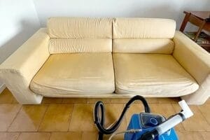 Un divano color crema dopo il Lavaggio Divani con un macchinario ad estrazione in primo piano, Saronno.
