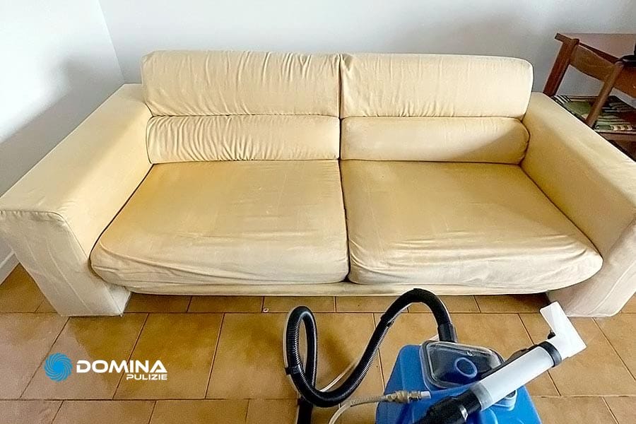 Un divano color crema dopo il Lavaggio Divani con un macchinario ad estrazione in primo piano, Saronno.