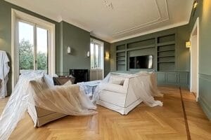 Un lussuoso soggiorno con pavimenti in legno, pareti verdi e grandi finestre si trova nel Centro Storico di Milano, pulito da Domina Pulizie.