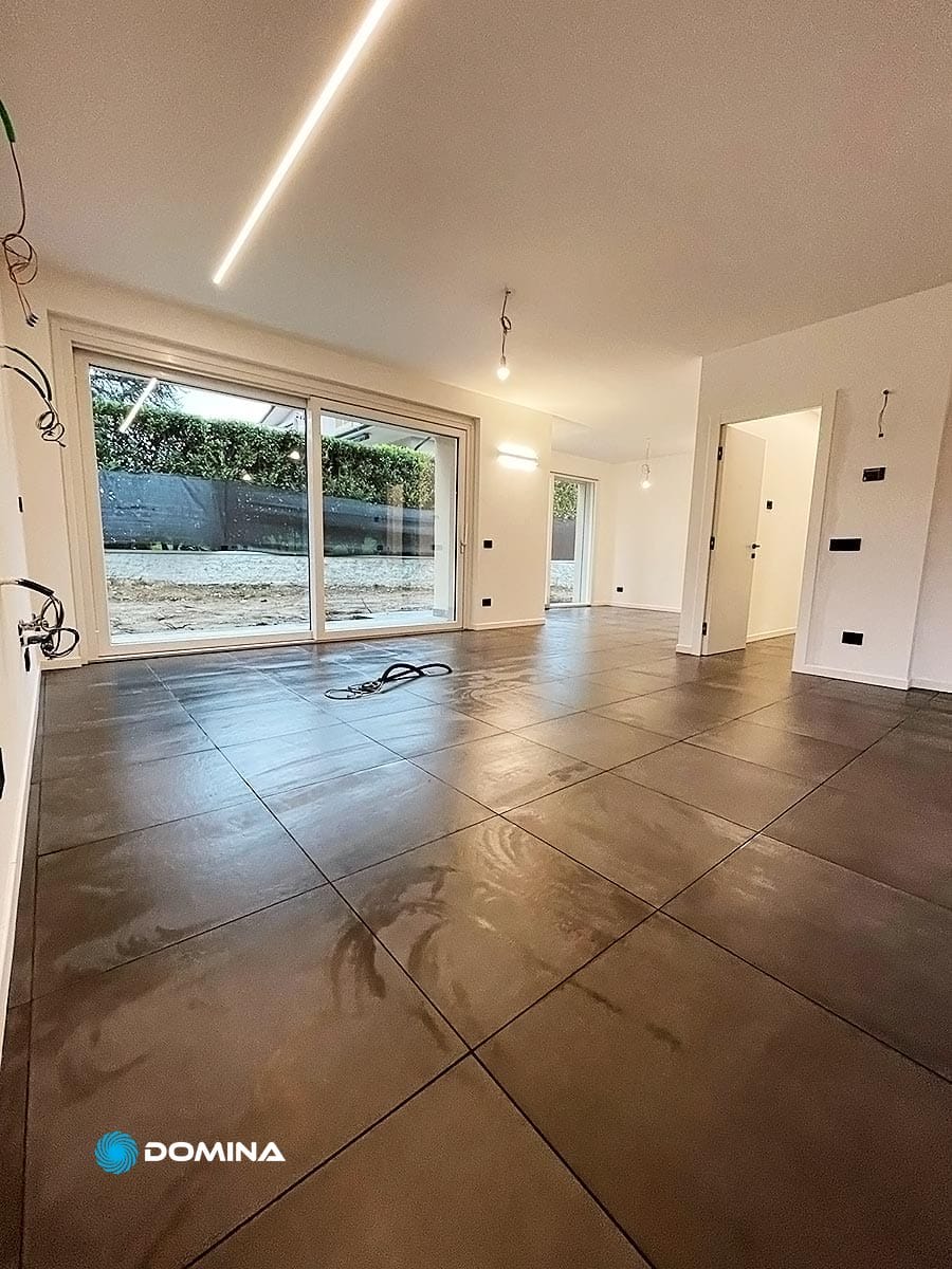 impresa-pulizie-como-1 Una camera moderna, non ammobiliata, con pavimento in piastrelle di grandi dimensioni, illuminazione ad incasso, un'ampia porta scorrevole in vetro e due porte interne. Il cablaggio elettrico è visibile sulle pareti e sul pavimento. Lo spazio è mantenuto meticolosamente da un'impresa di pulizie Como garantendo un ambiente incontaminato.