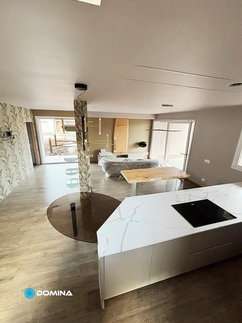 Moderno spazio abitativo open space nel Centro di Milano, con isola cucina con lussuoso piano di lavoro in marmo, tavolo da pranzo e zona soggiorno. Un'elegante colonna e ampie finestre permettono alla luce naturale di inondare questa residenza di lusso.