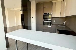 Cucina moderna con mobili eleganti, forno incorporato e un bancone minimalista. Toni neutri e superfici lisce dominano lo spazio, ideale per pulizie di lusso City Life Milano per mantenere il suo aspetto immacolato.