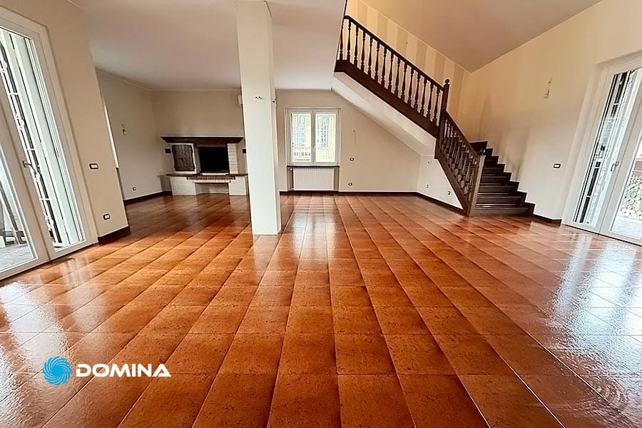 ev-pulizie-post-cantiere-milano-domina-pulizie-23032025 Ampia stanza in una villa a Milano con pavimento in piastrelle marroni, pareti bianche e una scala in legno scuro. Un camino impreziosisce l'angolo mentre grandi finestre lasciano entrare la luce naturale. Perfetta per chi cerca pulizie post ristrutturazione per aggiungere il tocco finale di perfezione.