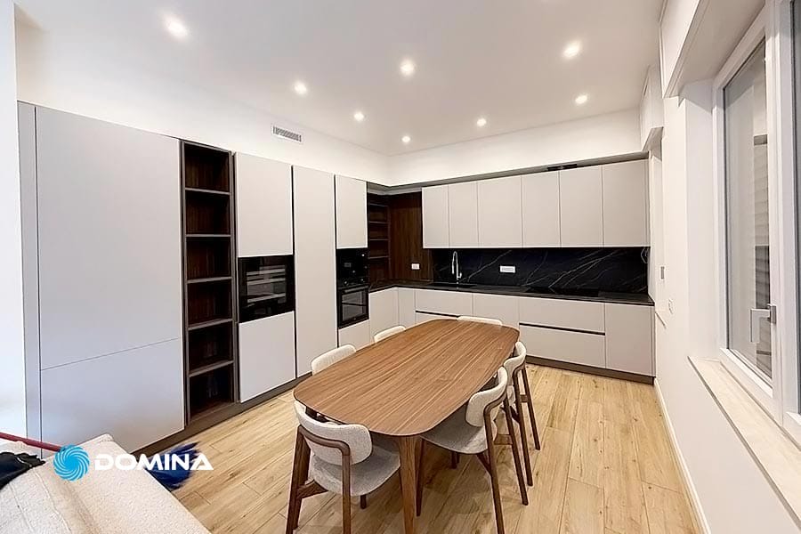 Cucina moderna con mobili chiari, paraschizzi nero, tavolo da pranzo in legno e sei sedie su pavimento in legno chiaro: ideale per Pulizie Primo Ingresso a Tradate per garantire che ogni dettaglio brilli fin dal primo giorno.