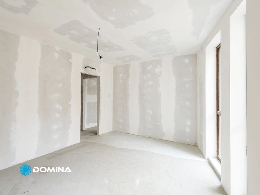 servizi-imbiancatura-6 Stanza incompiuta con muro a secco, cuciture a vista, pavimento nudo e un'ampia finestra che lascia entrare la luce naturale: perfetta per trasformare con un'imbianchino e i suoi servizi di imbiancatura professionale.
